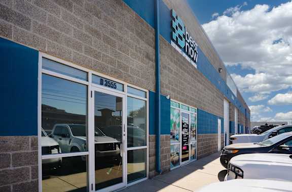A car dealership with a sign that says "E-Scooter" on the side of the building.