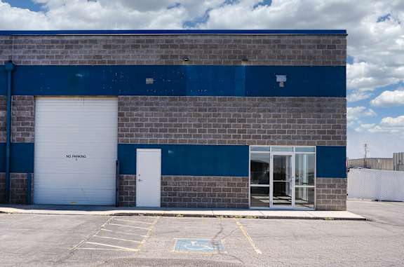 A blue and grey building with a white door and a sign that says "NO PARKING".