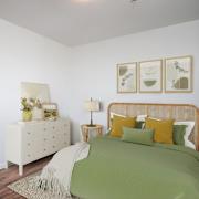 A bedroom with a bed, nightstand, and a plant on the nightstand.