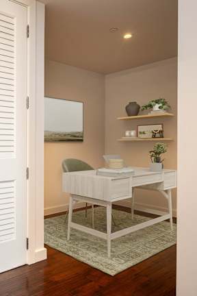 A white desk with a chair and a shelf with green plants.