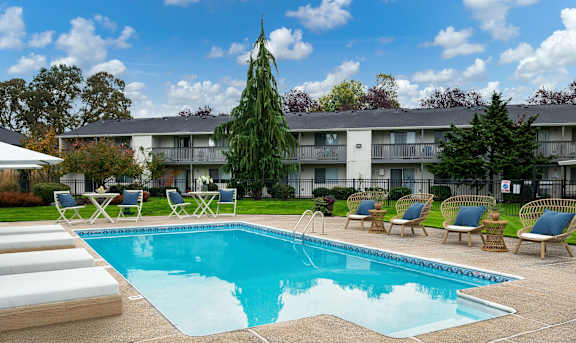 A swimming pool surrounded by lounge chairs and trees.