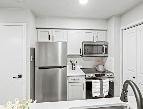 a kitchen with white cabinets and stainless steel appliances  at Carmel at Deerfield, San Antonio