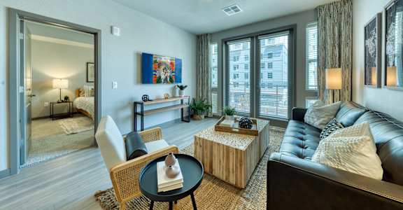 A living room with a black couch, a wooden coffee table, and a painting on the wall at The Rey Downtown, Phoenix, 85003