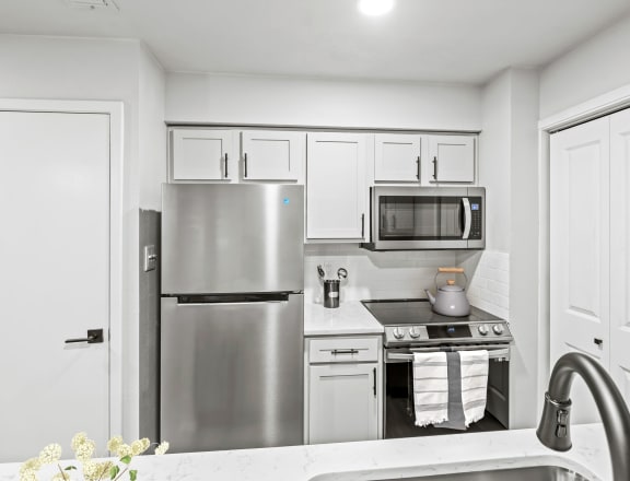 a kitchen with white cabinets and stainless steel appliances  at Carmel at Deerfield, San Antonio
