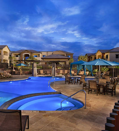 A swimming pool surrounded by chairs and umbrellas in a residential area.