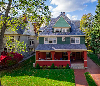 a green house with a red porch and a blue roof