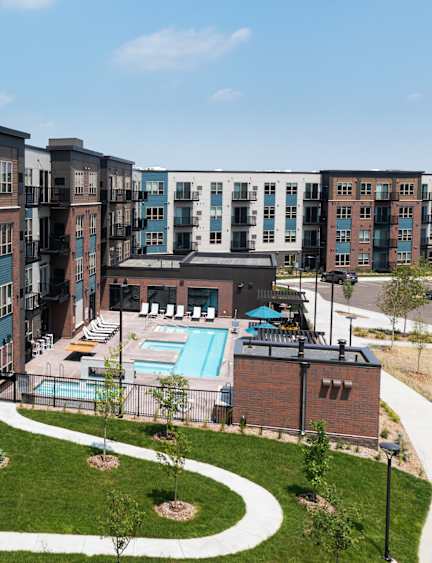 A large apartment complex with a pool and a fenced in yard.