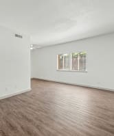 a spacious living room with white walls and wood flooring