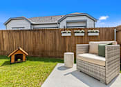 Thumbnail 3 of 5 - A backyard with a couch, chair, and dog house.