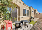 Thumbnail 4 of 6 - A patio with a table and chairs is in front of a house.
