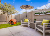 Thumbnail 4 of 5 - A patio with a grey couch, a small orange house, and a white umbrella  at Avilla Canyon, Phoenix