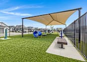 Thumbnail 5 of 8 - A playground with a slide, a bench and a shade structure.