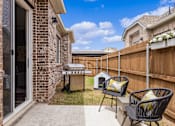 Thumbnail 5 of 6 - A backyard with a grill and two chairs.