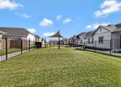 Thumbnail 4 of 6 - A grassy area in front of a row of houses with a black fence.