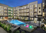 Thumbnail 5 of 31 - Resort-style courtyard pool with lounge seating, surrounding balconies, and evening lighting throughout the community