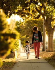 a mother and child walking down a sidewalk