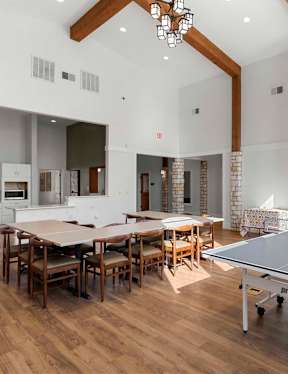 A ping pong table is in the middle of a room with a dining table and chairs.