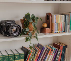a book shelf with books and a camera on it