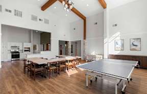 A ping pong table is in the middle of a room with a dining table and chairs.