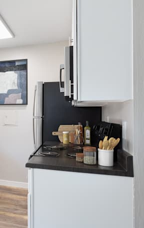 A kitchen with white cabinets and black countertops.