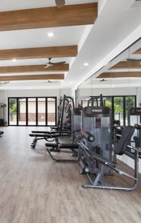 a gym with cardio equipment and windows