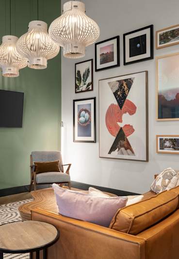 A living room with a brown couch, a wooden coffee table, a flat screen TV, and a green wall.