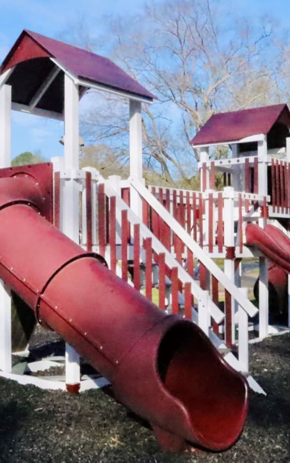 a playground with a red slide and a white playset at Uphill Flats, Georgia