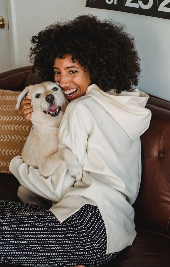 a woman sitting on a couch holding a dog