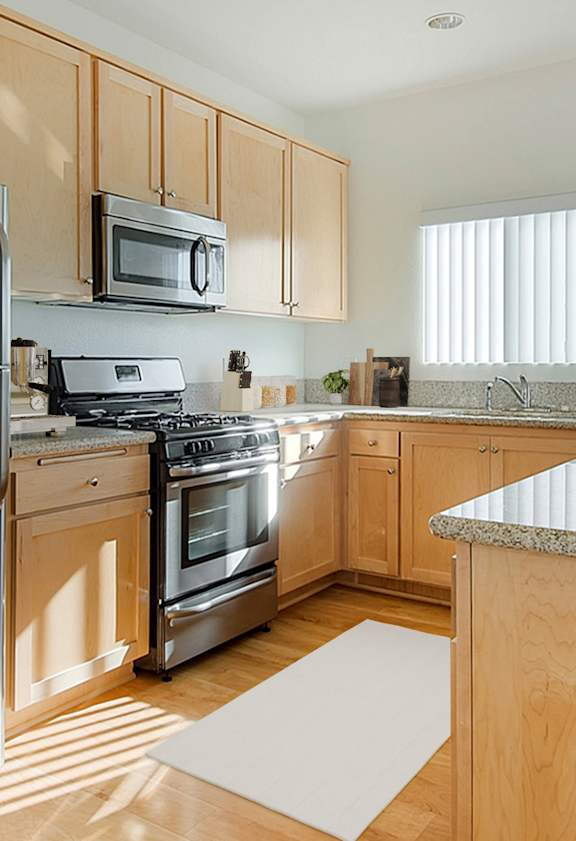 A kitchen with a refrigerator, microwave, oven, and sink.