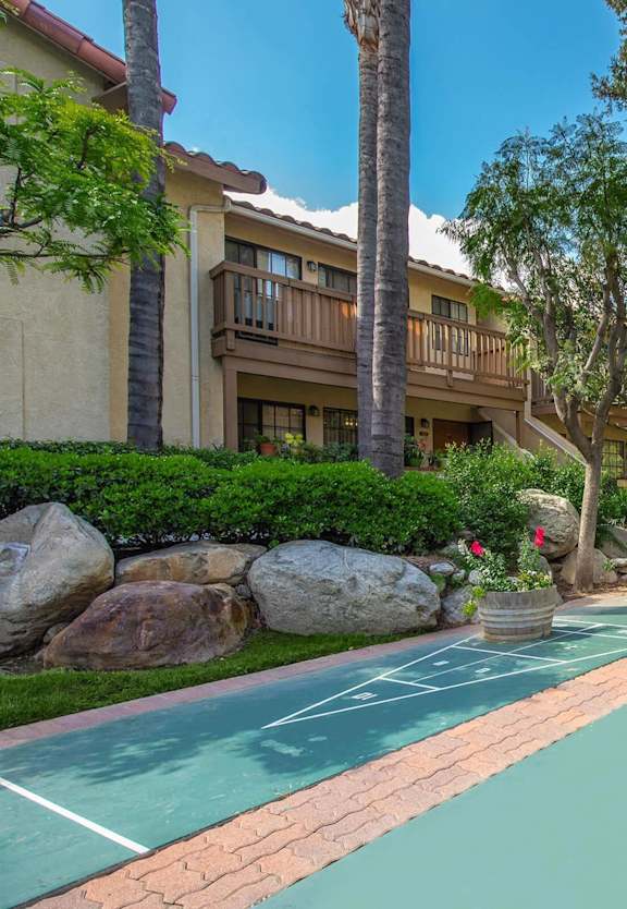 a basketball court is in the middle of a yard with trees and rocks at Victoria Springs Apartments, Riverside, California