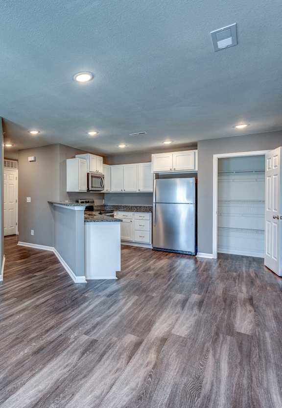 A kitchen with white cabinets and a wooden floor.
