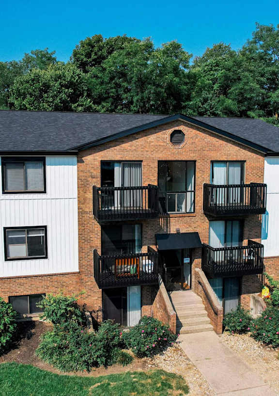 A large apartment building with a balcony and a small garden in front.