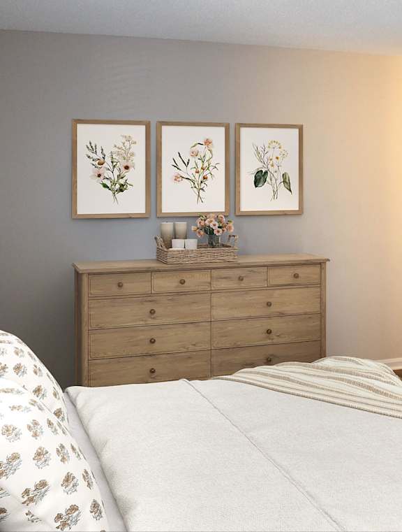A bedroom with a bed, dresser, and three framed pictures on the wall.