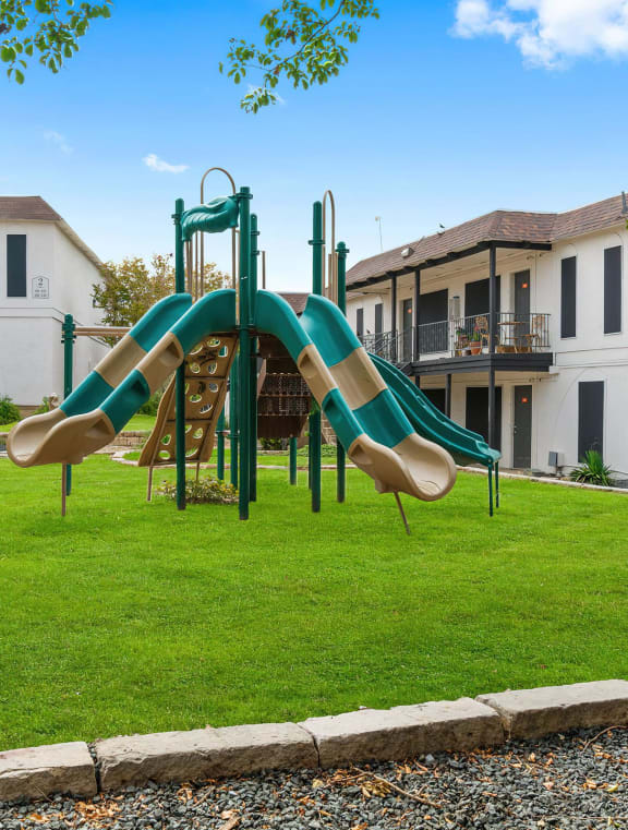 a courtyard with a playground and yellow chairs in front of an apartment building