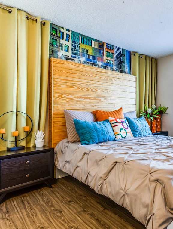 A bedroom with a bed, nightstand, and a window with blinds.