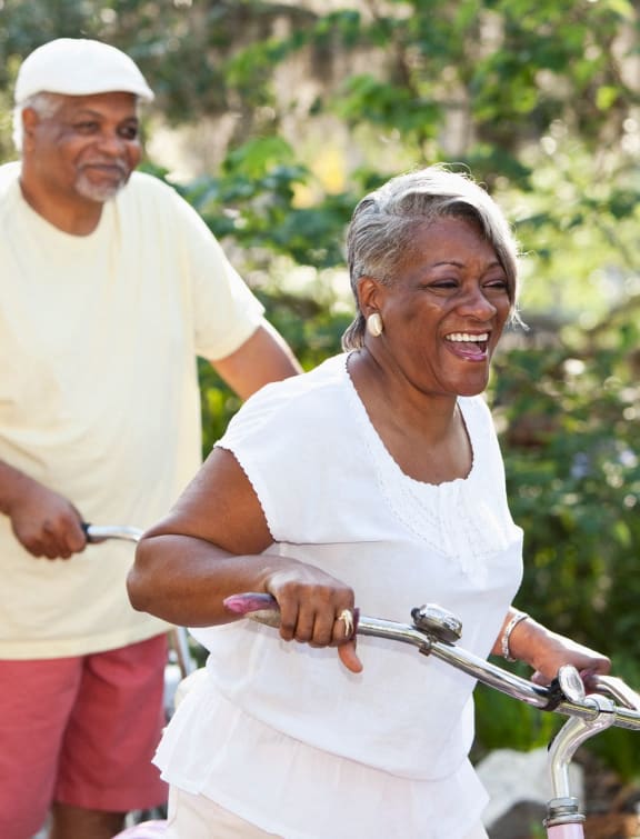 an older woman riding a bike with a man standing behind her