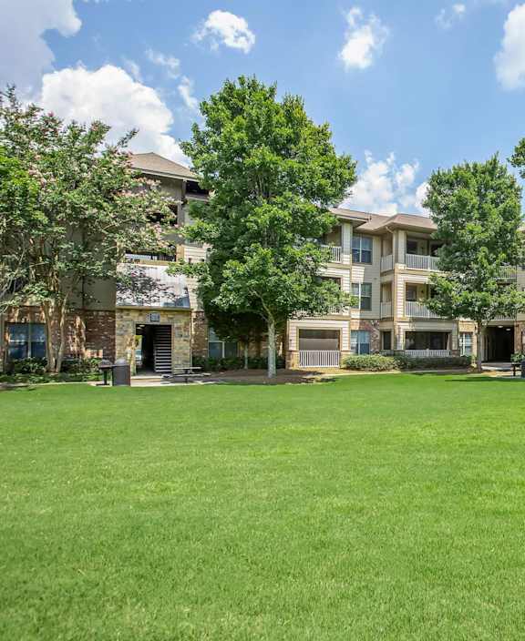 A grassy field in front of apartment buildings.