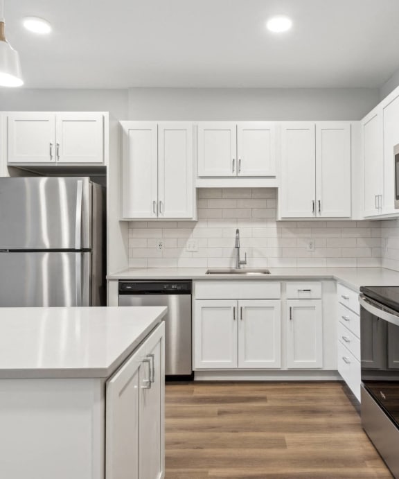 a white kitchen with stainless steel appliances and white cabinets
