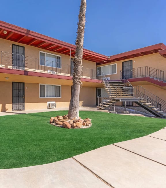 the courtyard of a building with a palm tree and green grass at Oakridge Apartments, Antioch, 94509