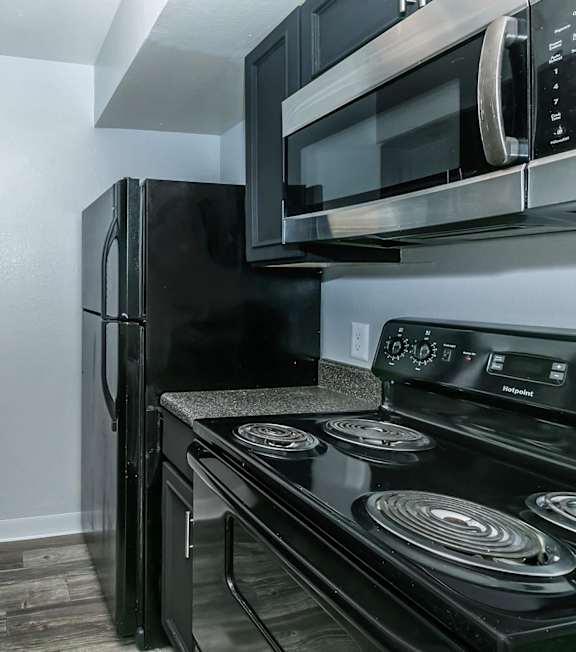 A black refrigerator and microwave in a kitchen.