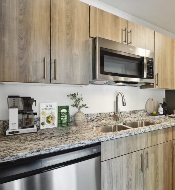 A kitchen with wooden cabinets and a stainless steel refrigerator. at Eden Commons, Eden Prairie, Minnesota