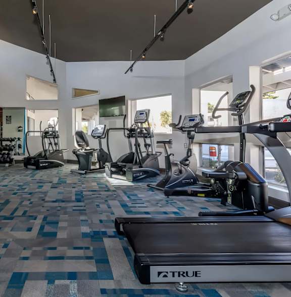 A gym with a variety of equipment including treadmills, weights, and exercise machines.