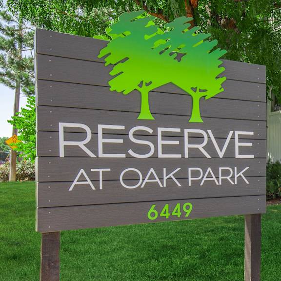 A sign for Reserve at Oak Park with a green tree graphic.