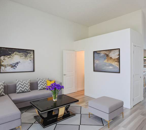 A modern living room with a grey sofa, a black coffee table, and two framed pictures on the wall.