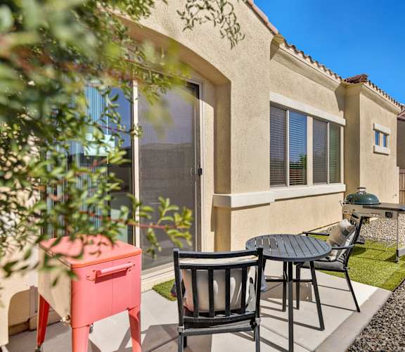 A patio with a table and chairs is in front of a house.