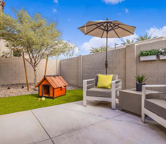 A patio with a grey couch, a small orange house, and a white umbrella  at Avilla Canyon, Phoenix