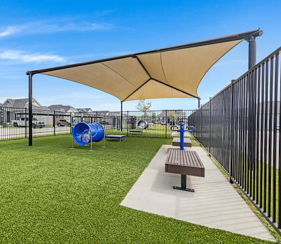 A playground with a slide, a bench and a shade structure.