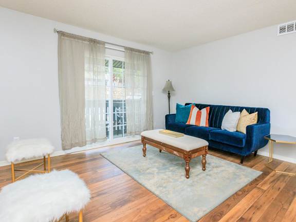 A blue couch with pillows sits in a room with a wooden floor and a rug.