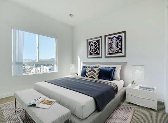 A bedroom with a large bed and two picture frames on the wall.