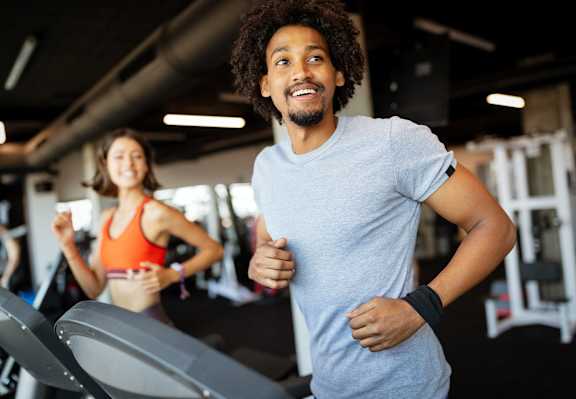 A man and a woman are working out in a gym.